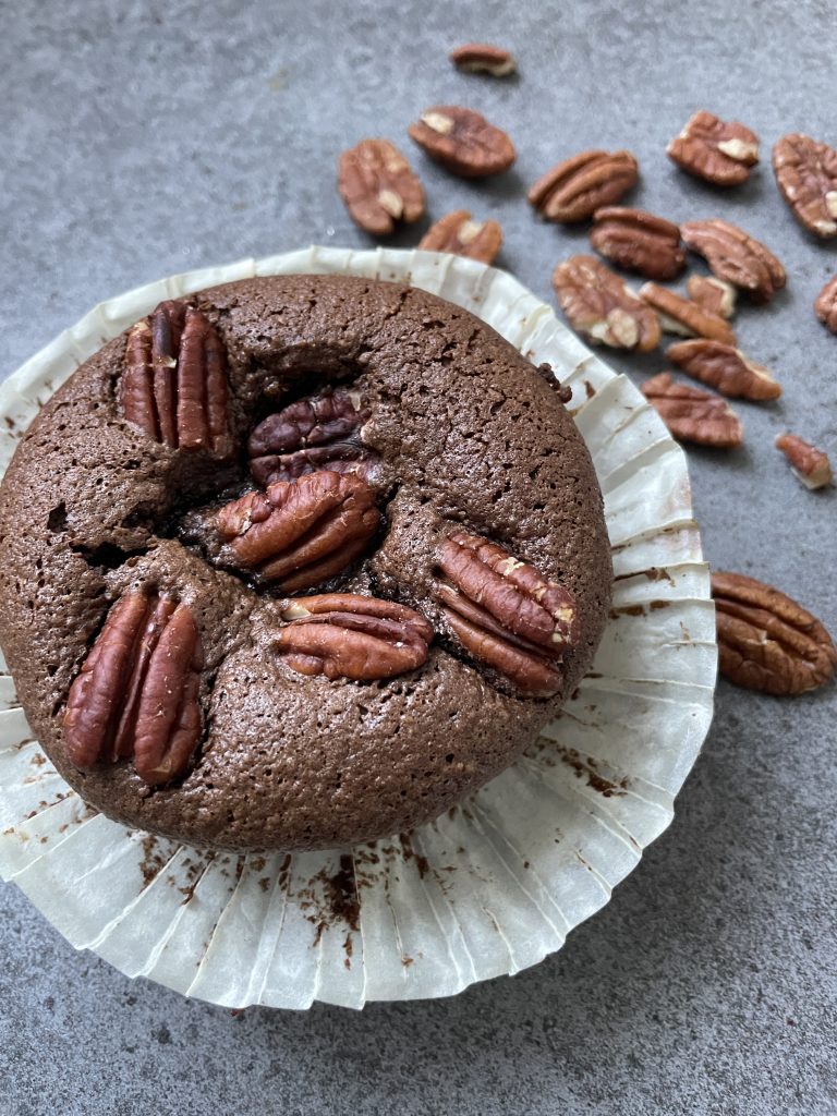 Chokladmuffins med mörk, saftig smet och en lätt sprucken topp, toppade med grovhackade pecannötter.
