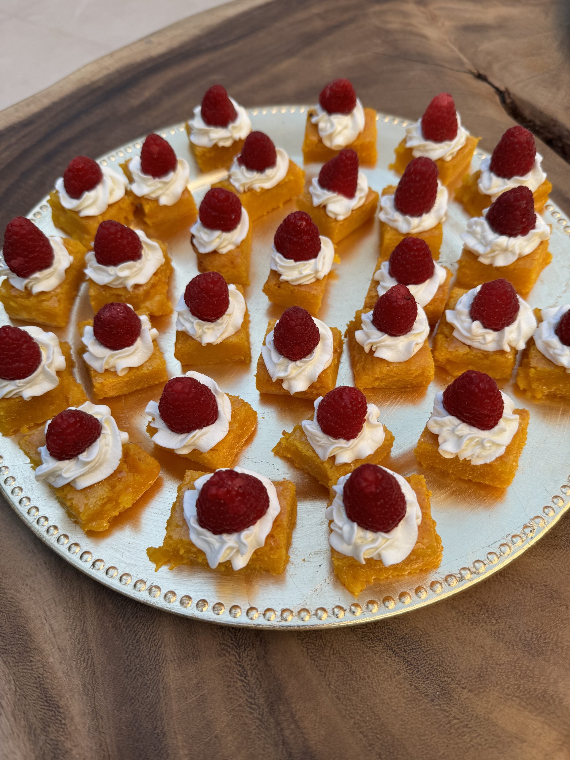 Saffranskladdkaka i bitar med vispad grädde och färska hallon på tallrik – juligt dessertrecept.