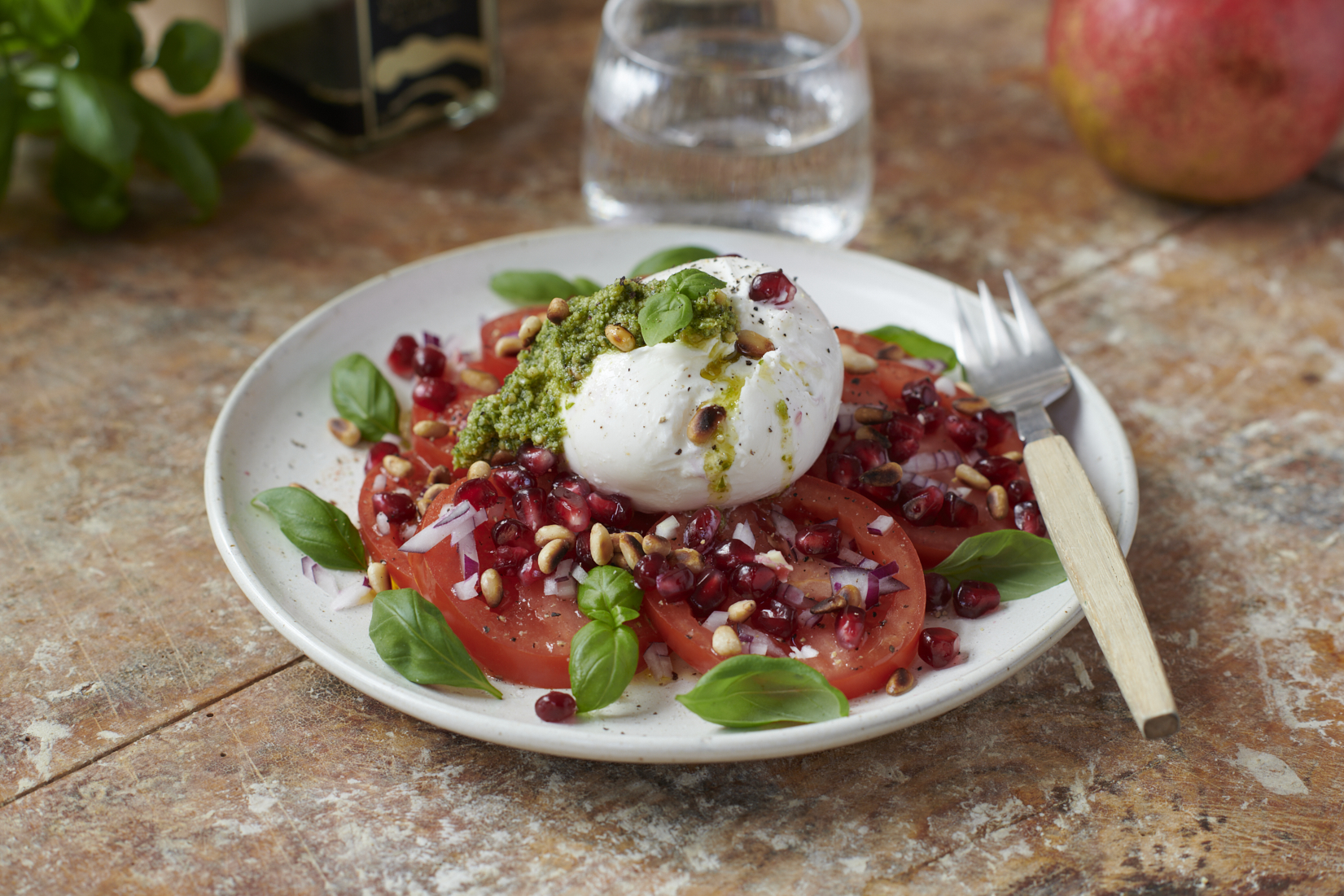 Nyttig rätt med burrata och färska tomater på vit tallrik, placerad på bronsfärgad rustik bakgrund